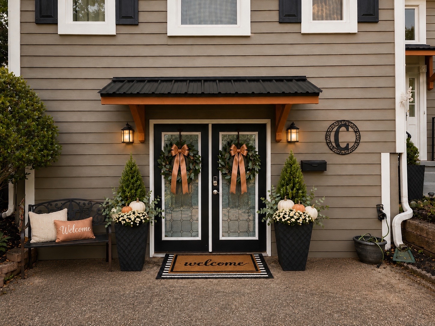 Black double doors styled with magnolia wreaths, copper bows, topiaries, and fall pumpkins